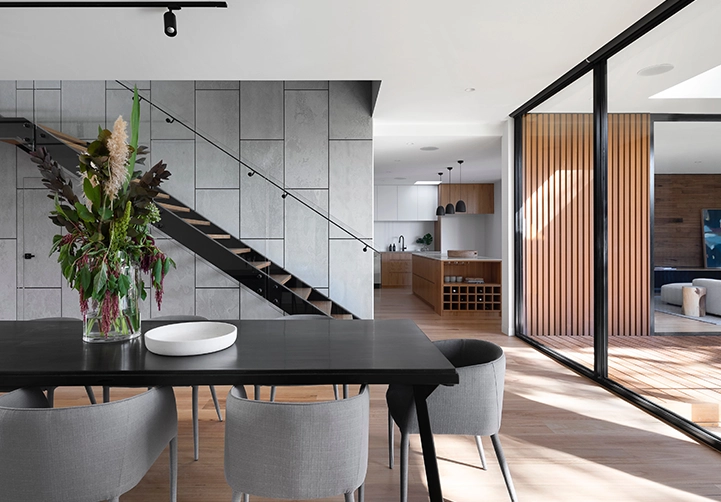 A dining room table with chairs and a vase of flowers.