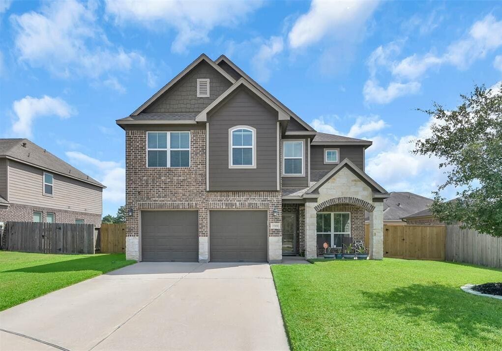 A large brick home with two garage doors.