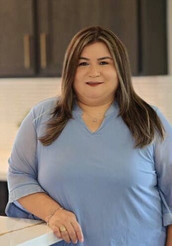 Smiling woman in blue blouse standing in kitchen