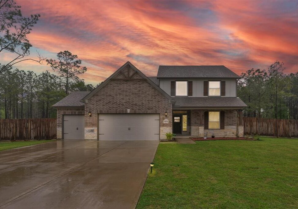 A house with a garage and driveway in front of the sunset.