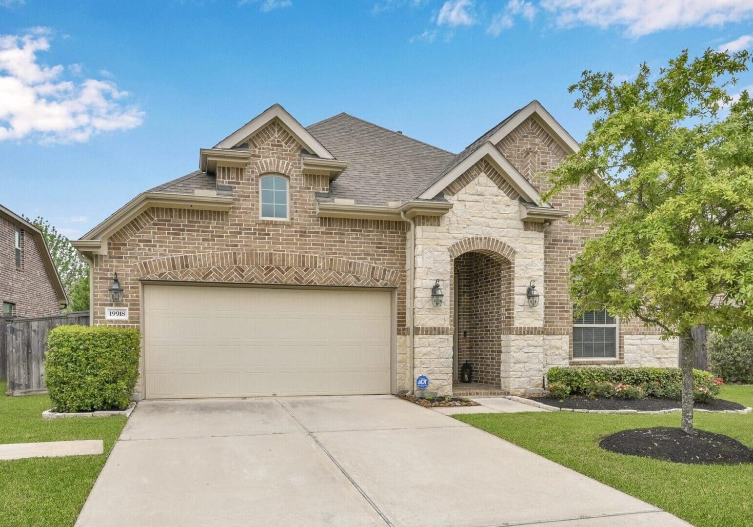 A large brick home with garage and driveway.