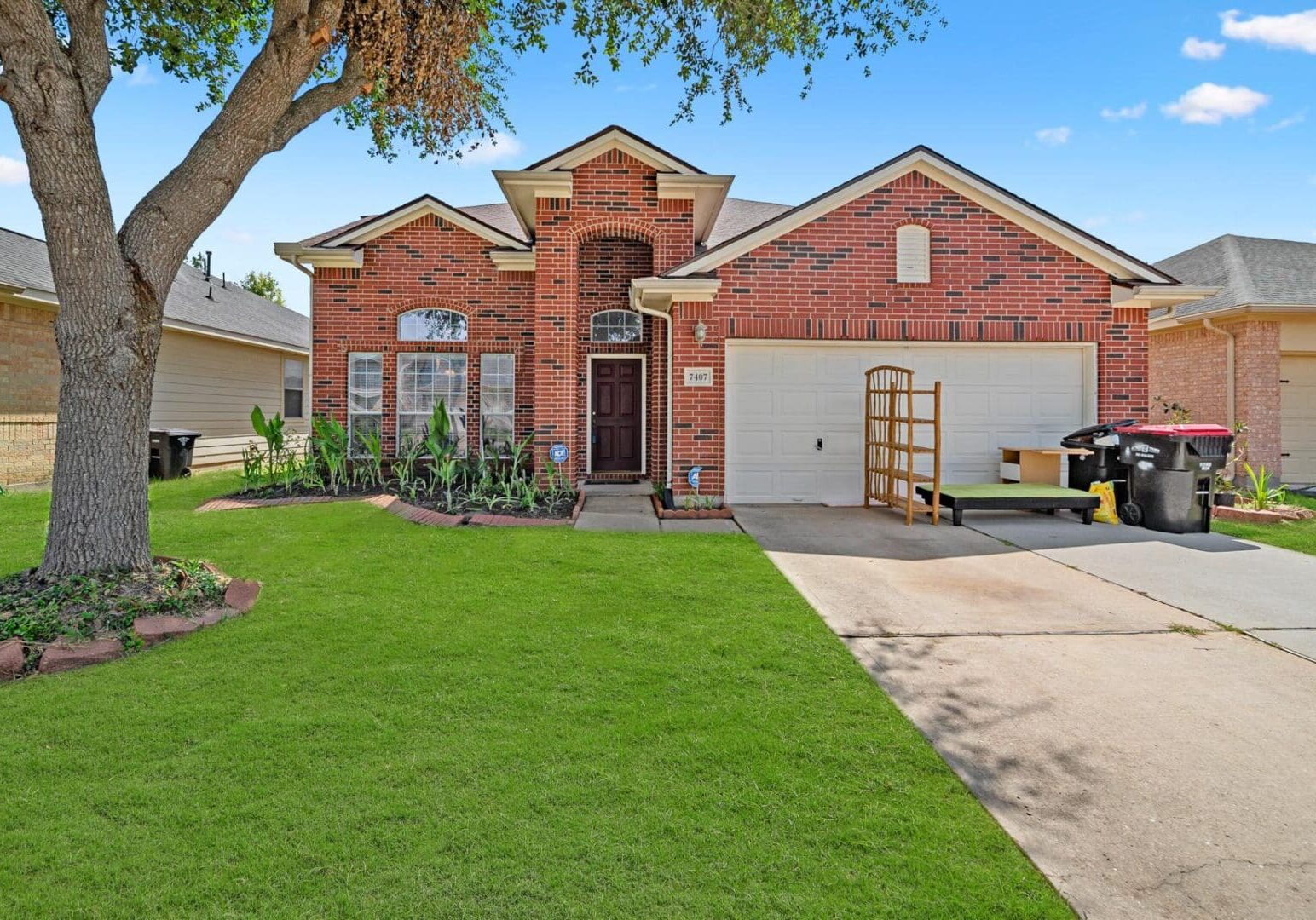 A brick home with a tree in the front yard.